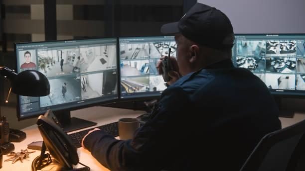 CCTV operator watching live camera screens and using a radio