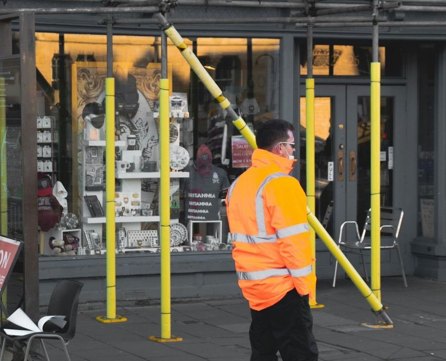 Security guard in a high-visibility jacket outside a building with scaffolding