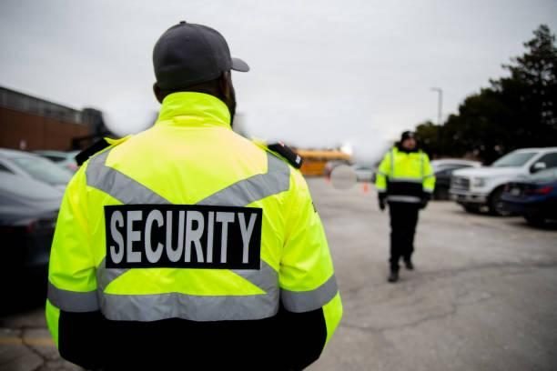 Security guards in high-visibility jackets patrolling a car park